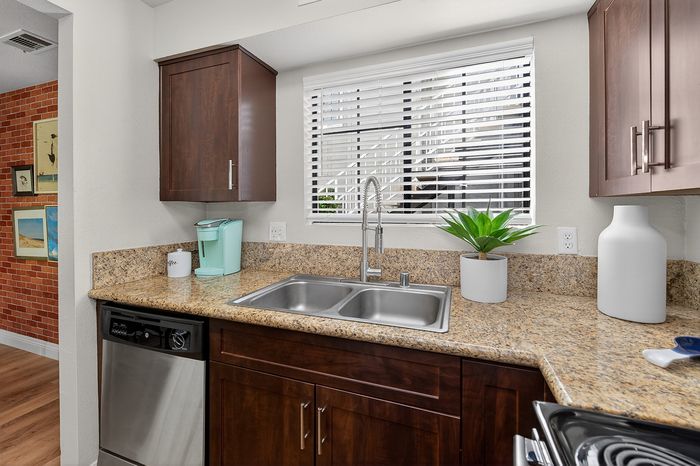 Modern kitchen with granite countertops, stainless steel appliances, stylish cabinetry, and a bright window view.
