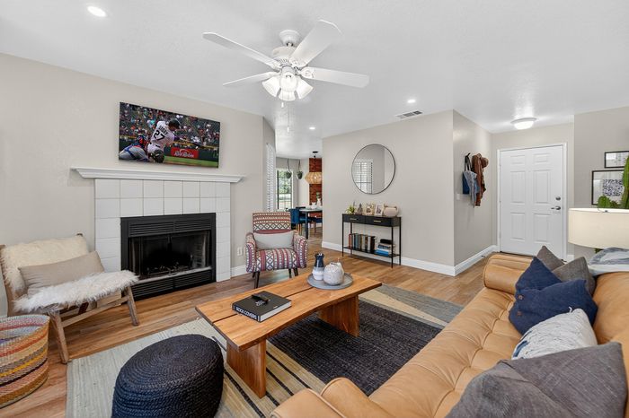 Inviting living room with cozy fireplace and modern décor, featuring a stylish brown leather sofa and vibrant accent chairs.