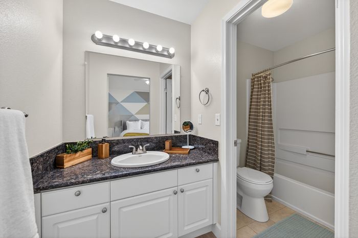 Modern bathroom with sleek vanity, granite countertop, and chic lighting, providing a glimpse into a stylish bedroom.