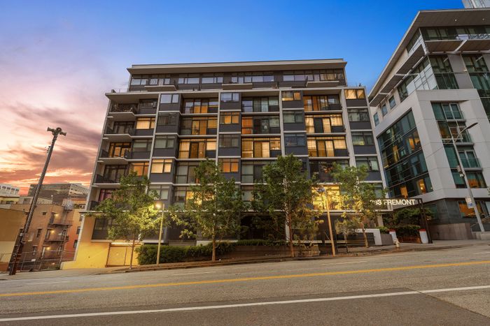 Modern apartment building with sleek glass windows and lush greenery at the twilight sky backdrop, highlighting urban living at 333 Fremont.
