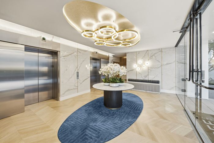 Luxurious lobby with elegant lighting, marble walls, and a chic centerpiece adorned with orchids, offering a sophisticated entrance ambiance.