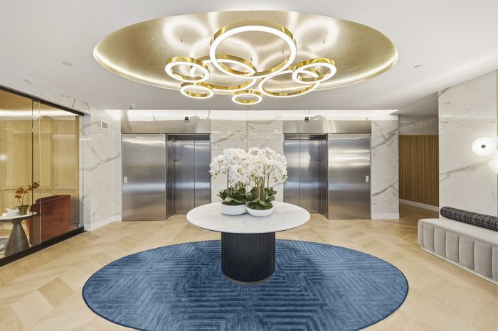 Luxurious apartment lobby featuring a stunning modern chandelier, elegant marble walls, and a stylish centerpiece with white orchids.