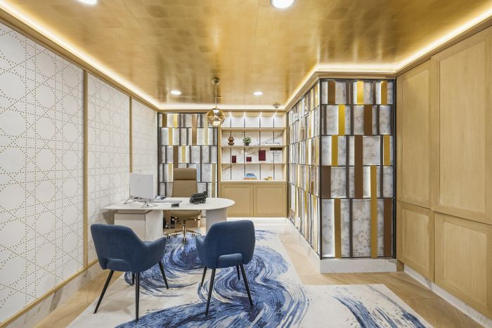 Luxurious office space featuring modern decor with golden accents, cozy seating, and stylish shelving.