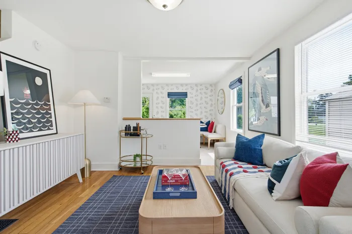 Bright and inviting living room featuring a modern interior with a cozy couch, vibrant pillows, and elegant artwork. The room is adorned with natural light and stylish decor, providing a perfect blend of comfort and sophistication.