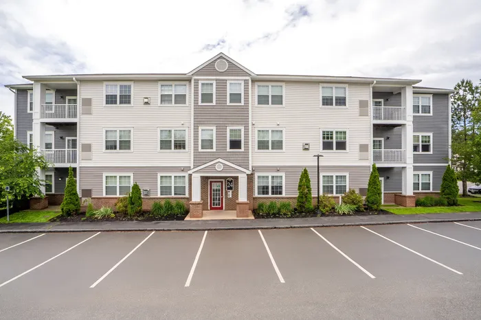 Modern apartment building with three floors, featuring stylish siding, well-maintained landscaping, and ample parking space.