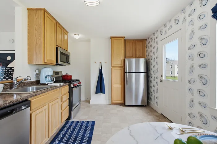 Bright and inviting kitchen featuring modern stainless steel appliances, elegant wooden cabinets, and a chic blue and white patterned wall.