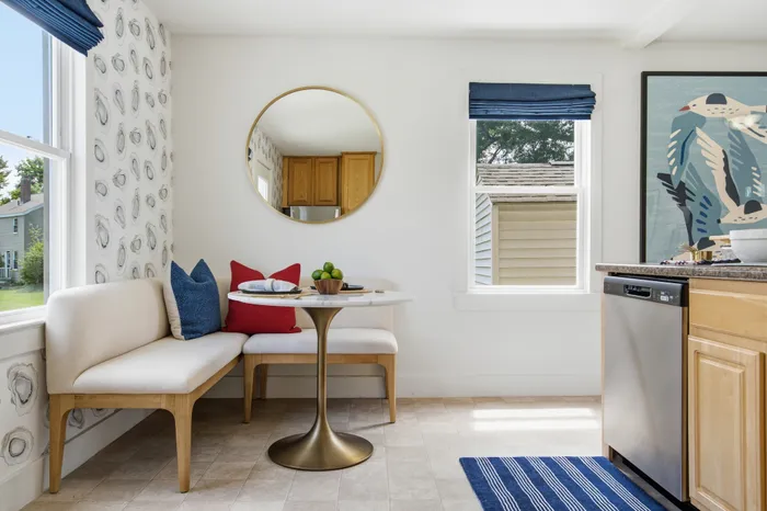 Bright and inviting kitchen nook featuring a chic marble table, modern art, and cozy benches with colorful cushions.