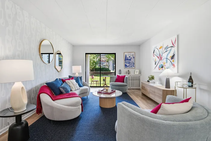 Stylishly decorated living room with modern furniture, vibrant art, and natural light from a garden-view patio.