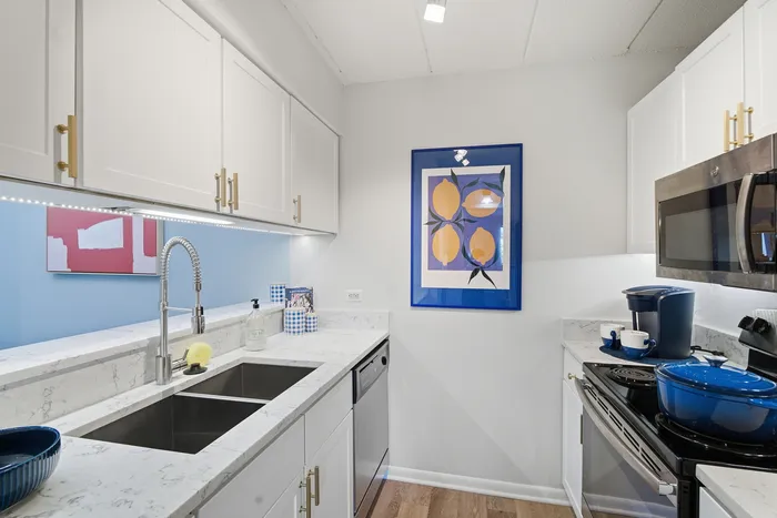 Chic modern kitchen featuring sleek white cabinetry, marble countertops, and vibrant lemon artwork for a playful touch.