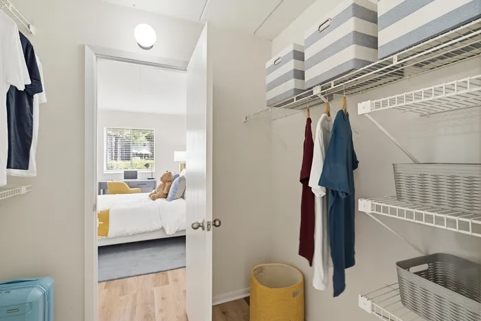 Inviting walk-in closet with organized shelves, hanging space, and bright natural light leading to a cozy bedroom.