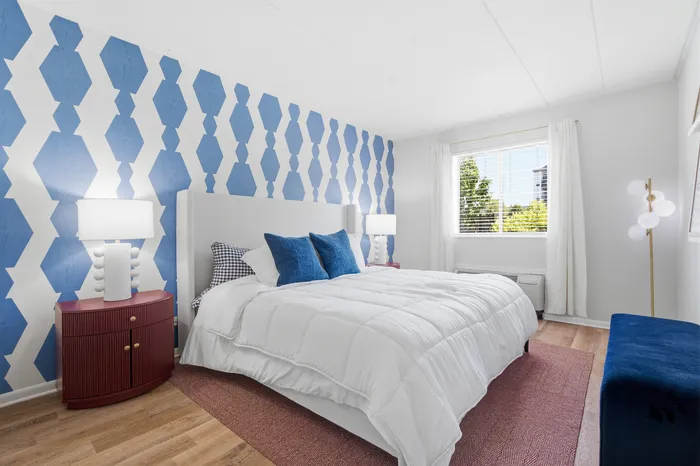 Inviting bedroom with bold geometric wallpaper, cozy white bedding, and stylish decor, perfect for a restful retreat.