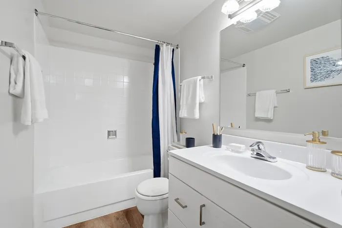 Modern bathroom featuring sleek white cabinetry, elegant fixtures, and a stylish tub with a vibrant curtain.