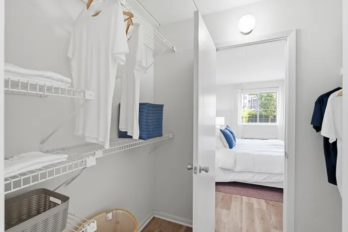Bright and organized closet with shelves and hangers, leading to a cozy bedroom filled with natural light.