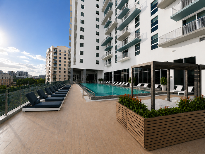 Luxurious high-rise apartment exterior showcasing a pristine rooftop pool, elegant lounge chairs, and modern cityscape views.