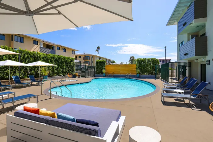 Inviting outdoor pool area with modern lounge chairs, vibrant cushions, and shady umbrellas, perfect for relaxation and enjoyment.