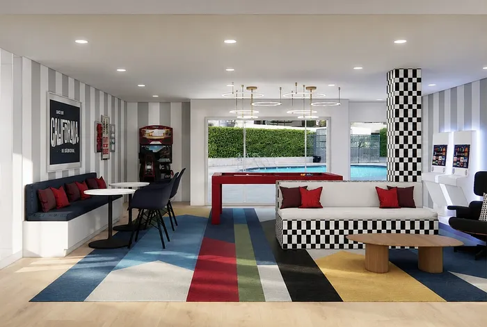 Chic lounge area with bold striped decor, vibrant accent pillows, and sleek furnishings, overlooking a refreshing pool view.