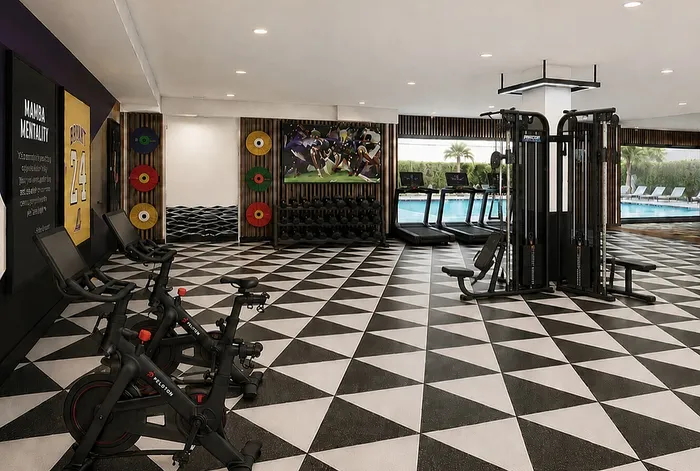 Modern gym with sleek geometric flooring, featuring state-of-the-art exercise bikes and treadmills, with a pool view for an immersive workout experience.