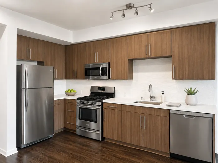 Modern kitchen with sleek stainless steel appliances, warm wooden cabinetry, and elegant track lighting.