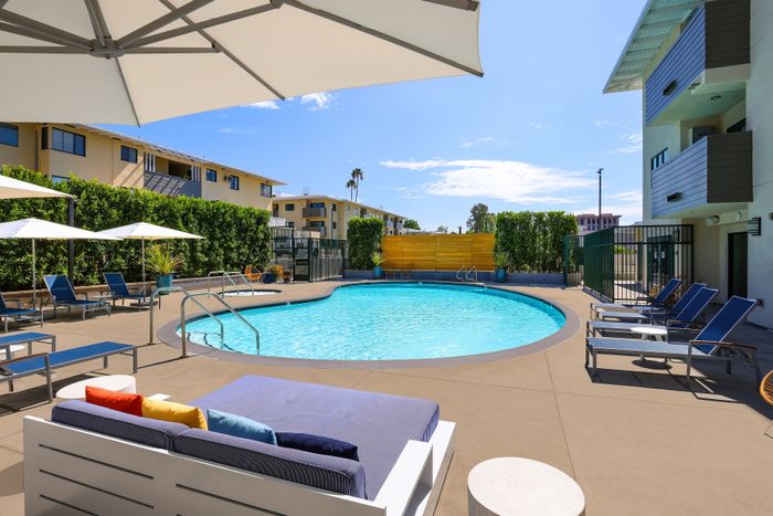 Inviting outdoor pool area with modern lounge chairs, vibrant cushions, and shady umbrellas, perfect for relaxation and enjoyment.