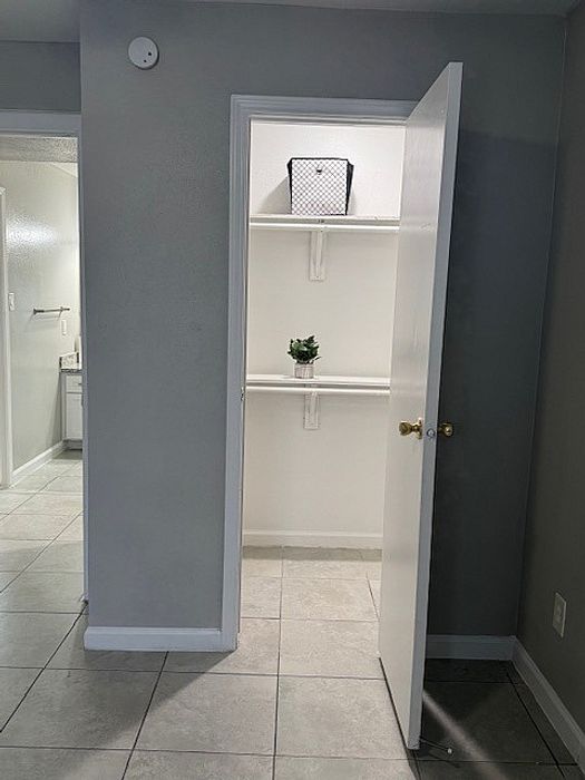 Inviting closet view with modern shelving and elegant bathroom access in a stylish apartment.