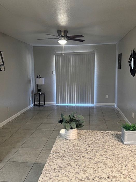 Bright and inviting open space with stylish tile flooring, a ceiling fan, and natural light from sliding doors, perfect for a modern living area.