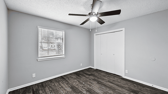 Bright and airy room with sleek hardwood floors, modern ceiling fan, and ample closet space.