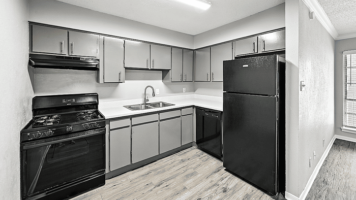 Modern kitchen with sleek black appliances, stylish cabinetry, and elegant countertops on a wood-style floor.