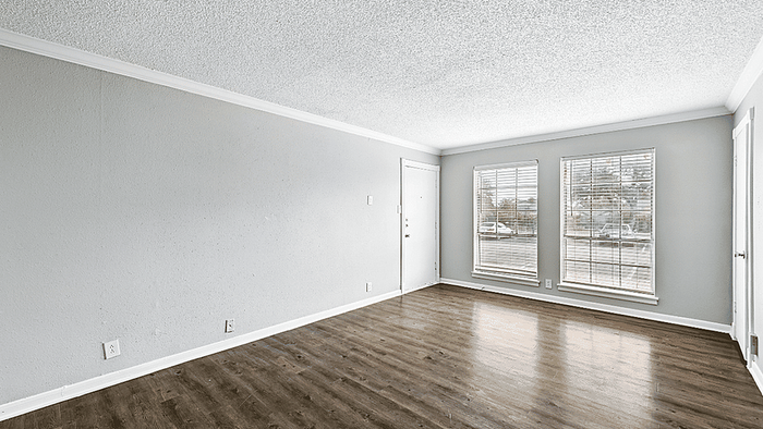Bright and spacious empty living room with large windows and sleek hardwood flooring, ideal for customization and design.