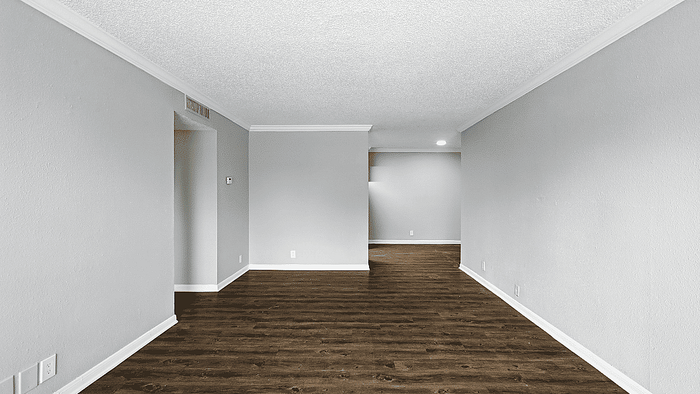 Spacious apartment interior featuring sleek hardwood floors, elegant crown molding, and ample natural lighting.