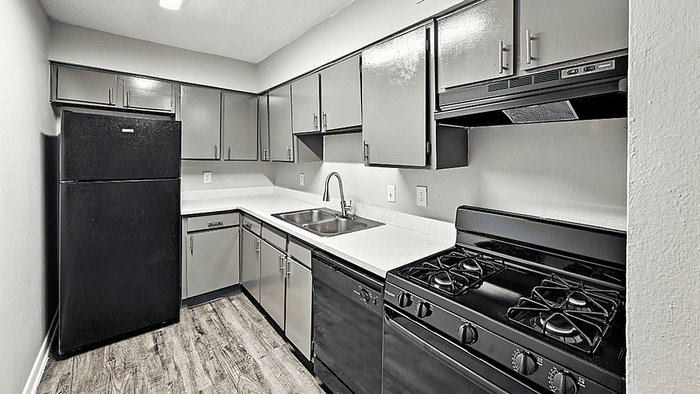 Modern U-shaped kitchen with sleek cabinetry, stainless steel sink, and black appliances on elegant wood flooring.