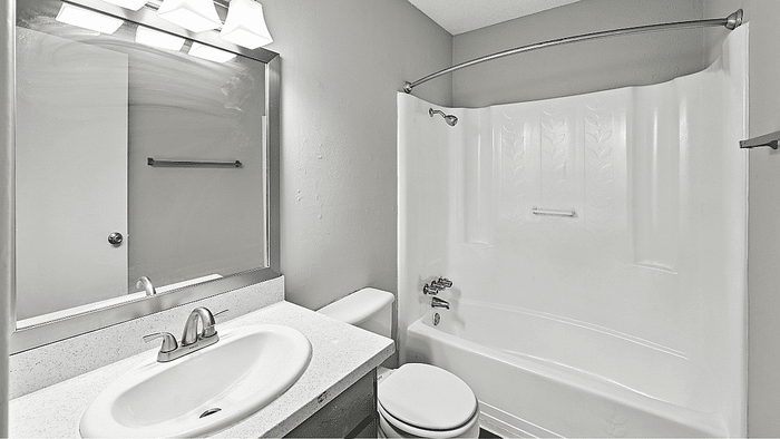 Sleek and modern bathroom with elegant fixtures, featuring a pristine bathtub and large mirror for a refreshing experience.