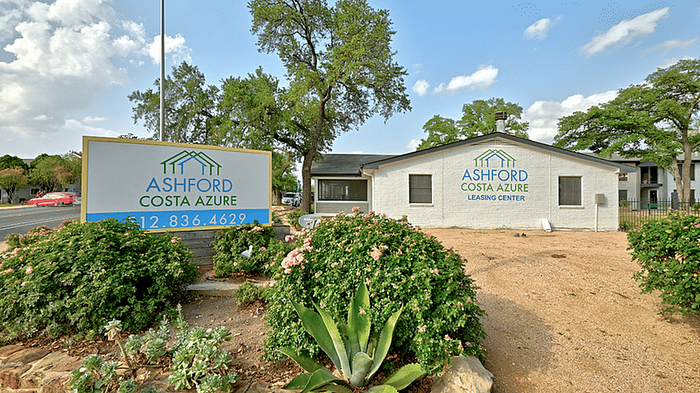 Welcome to Ashford Costa Azure Leasing Center, surrounded by lush greenery and vibrant landscaping under a clear blue sky.