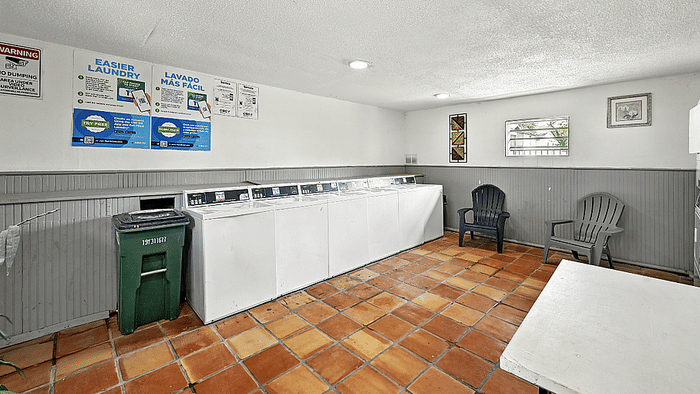 Inviting laundry room with modern washing machines, cheerful terracotta tiles, and comfortable seating.