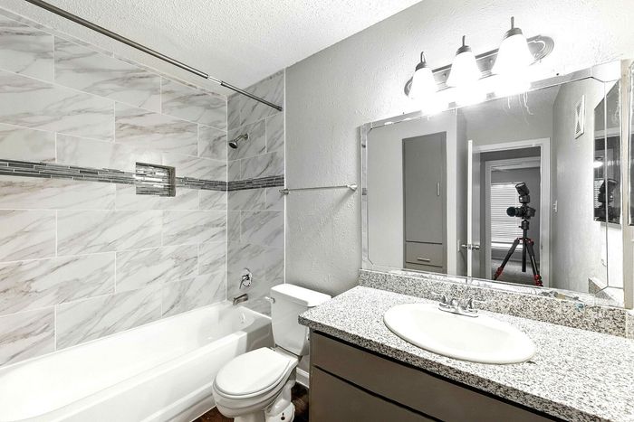 Modern bathroom featuring elegant marble tiles, a sleek granite countertop, and stylish lighting, offering a luxurious and inviting atmosphere.