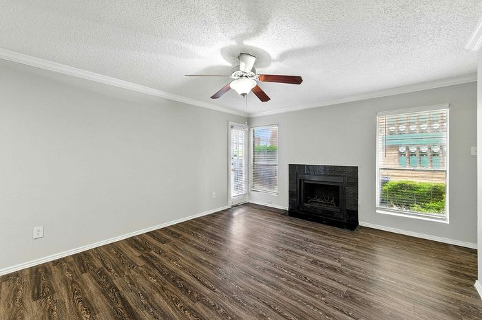 Elegant living room with rich wooden floors, a cozy fireplace, and large windows filling the space with natural light.