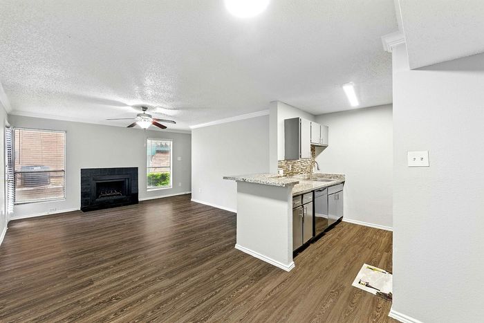 Chic open-plan living area with a cozy fireplace, modern kitchen with granite countertops, and elegant wood flooring.