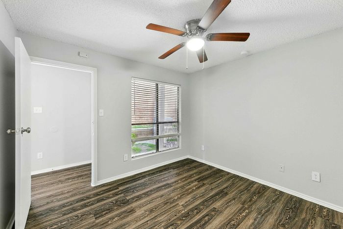 Bright and inviting bedroom with elegant wood flooring, ceiling fan, and a large window for natural light.