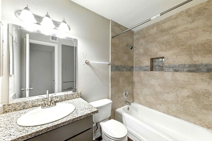 Modern bathroom with elegant granite countertop, stylish lighting, and chic tiled bathtub, offering a serene and luxurious bathing experience.
