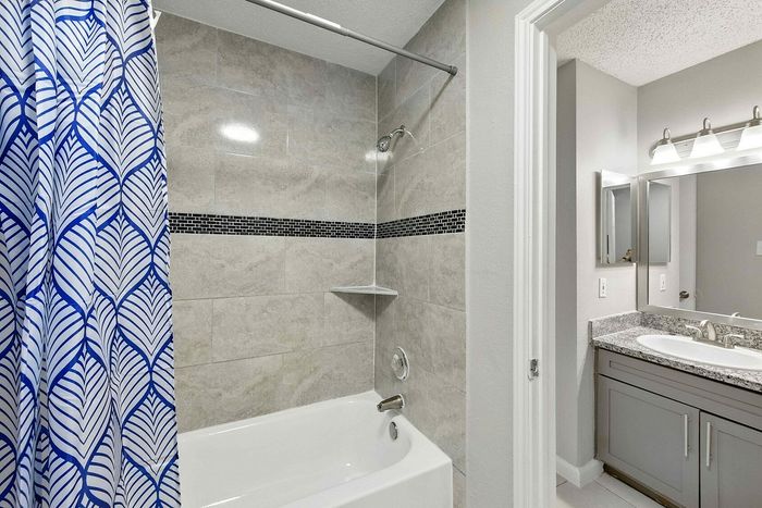 Modern bathroom featuring elegant tile work, sleek granite countertop, and vibrant blue shower curtain for a touch of sophistication.