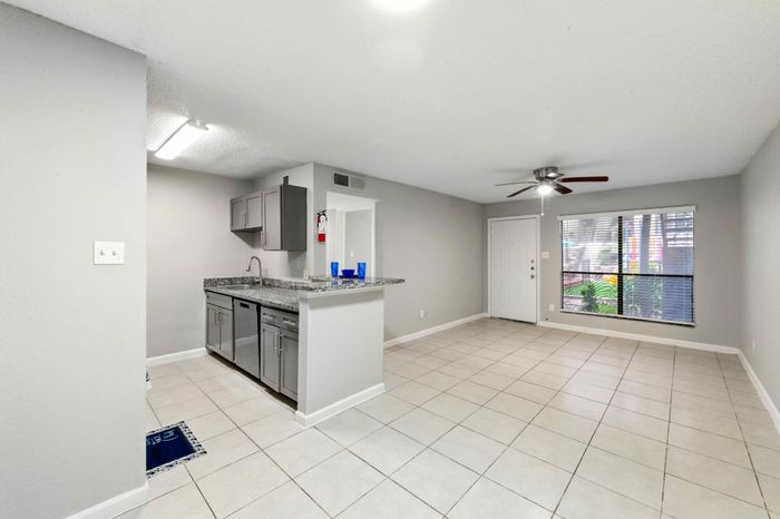 Bright open-plan apartment featuring a sleek kitchen with granite countertops, modern cabinets, and a spacious living area with large windows.