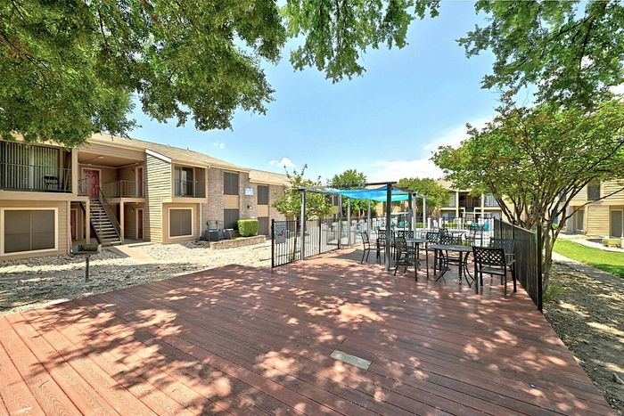 Inviting apartment complex with spacious outdoor deck, shaded seating, and lush greenery perfect for relaxation.