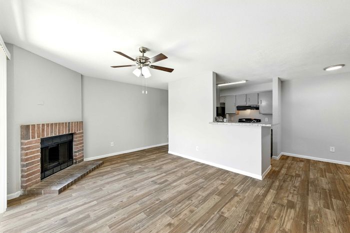 Modern open-concept living space with elegant hardwood floors, a cozy fireplace, and a stylish kitchen featuring stainless steel appliances.