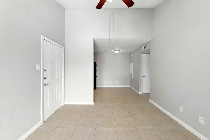 Inviting apartment entryway showcasing modern tile flooring and soft grey walls, leading to a cozy living space.