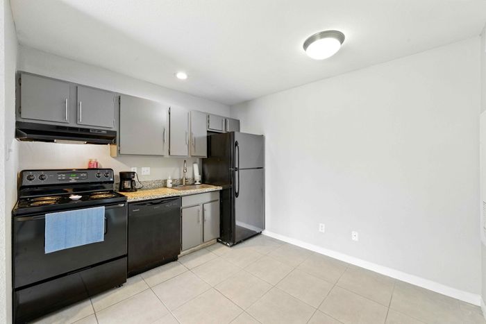 Modern kitchen with sleek gray cabinets, granite countertops, and stainless steel appliances, offering ample space for culinary creativity.