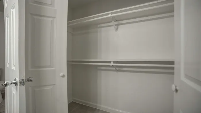 Spacious and modern walk-in closet with double hanging rods and sleek white doors, perfect for stylish storage solutions.