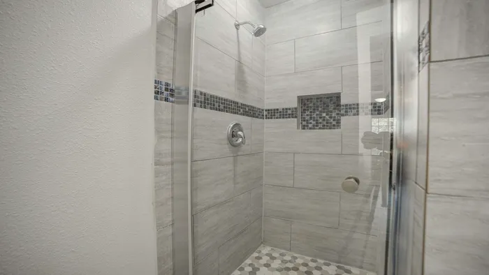 Modern walk-in shower with elegant tilework and sleek fixtures, enhancing bathroom luxury.