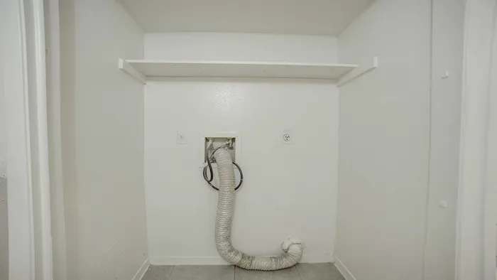 Spacious laundry area with modern utility hookups and elegant overhead shelving.
