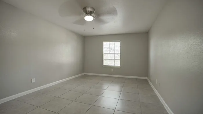 Spacious and bright room with sleek tiled flooring and a modern ceiling fan, offering a blank canvas for your personal touch.