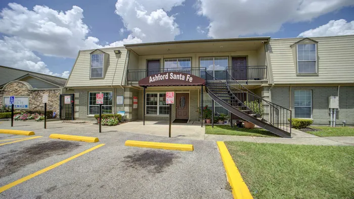 Charming Ashford Santa Fe apartment exterior with elegant staircase, lush landscaping, and sunny skies highlighting a welcoming community entrance.