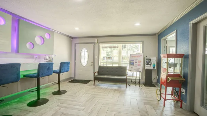 Modern apartment lobby with stylish seating, vibrant blue bar stools, and a classic popcorn machine adding a touch of fun.